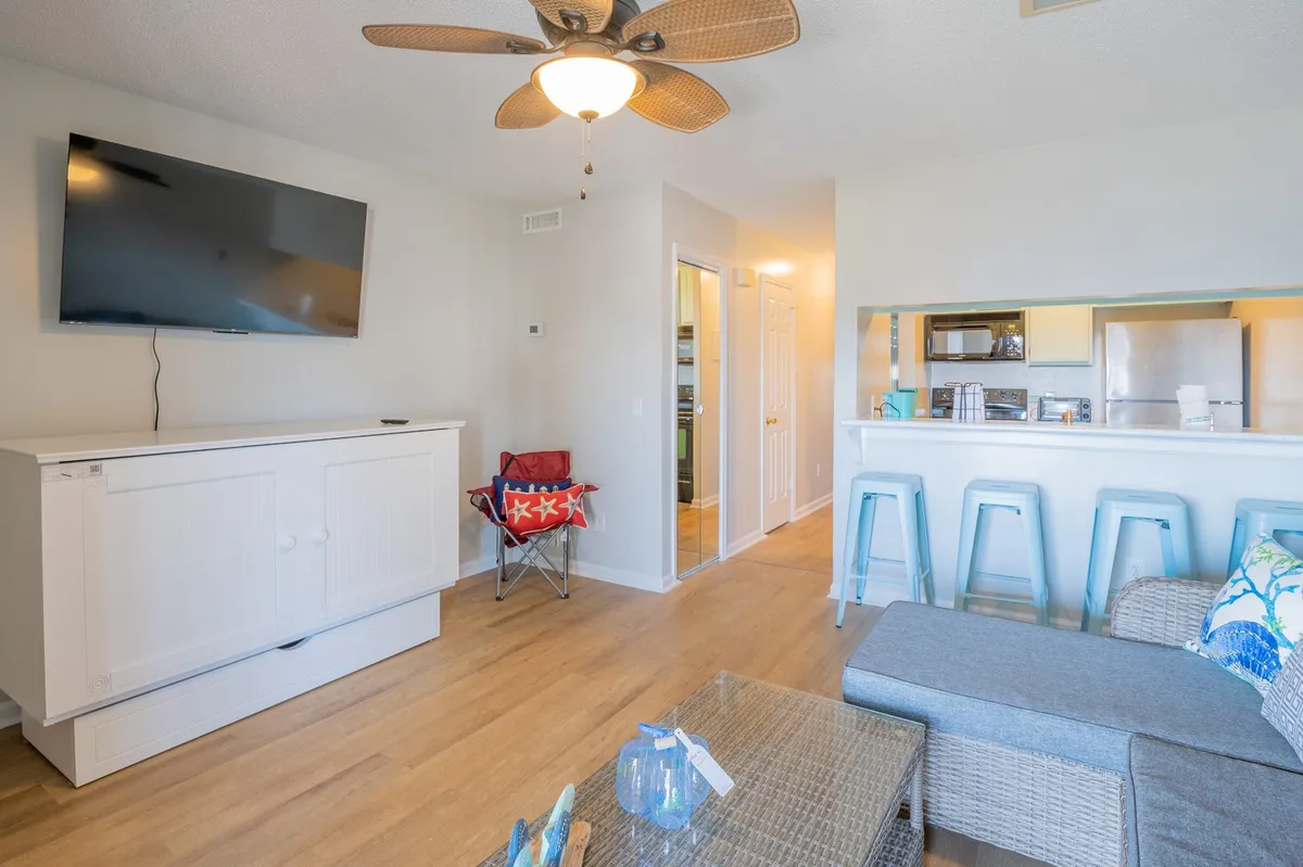 A bright, open-plan interior that seamlessly connects a comfortable seating area, a bar counter, and the kitchen beyond. This setup fosters easy socializing, whether guests are cooking, relaxing, or watching TV together.