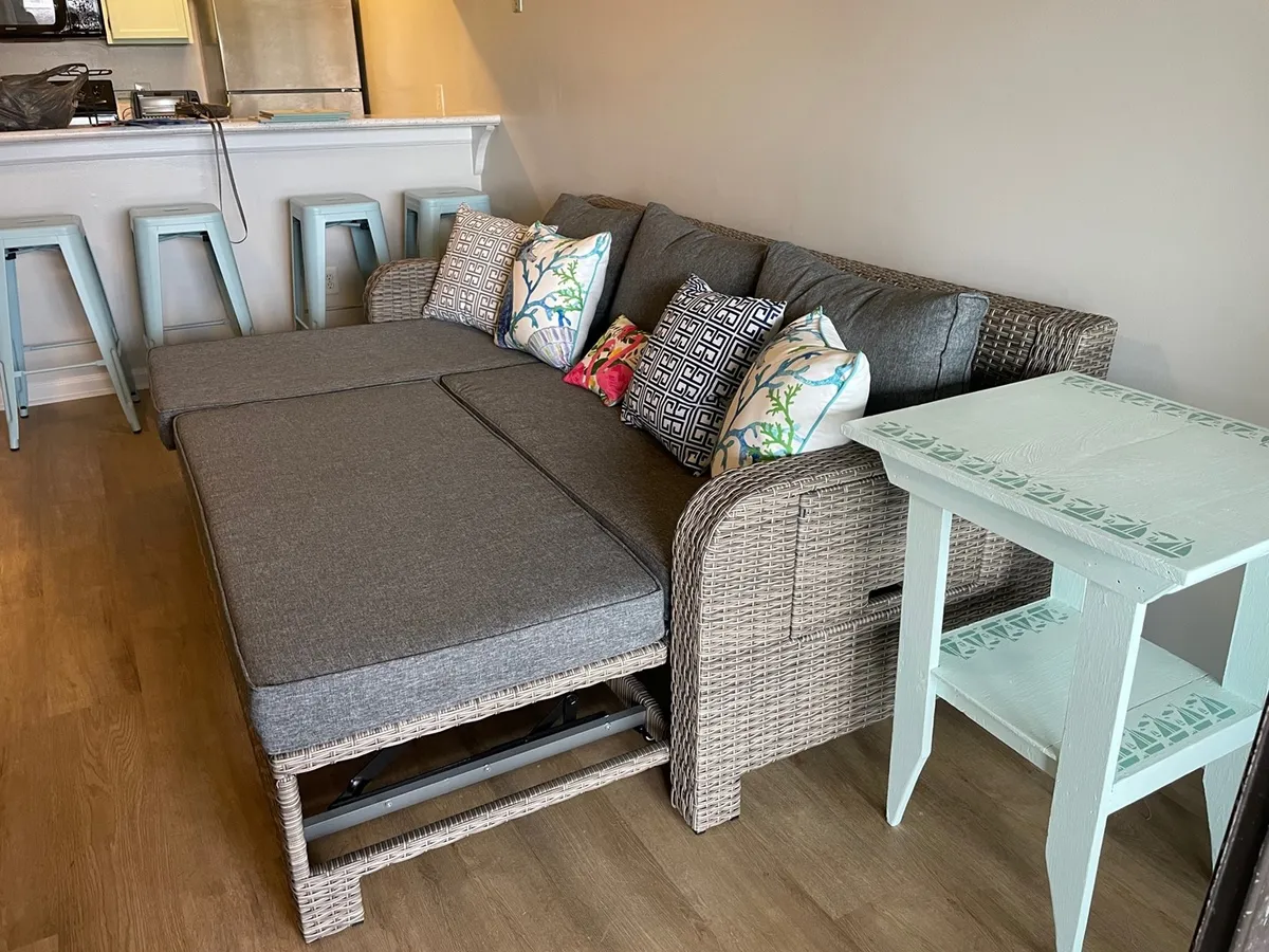 A spacious living area featuring a sectional sofa, decorative pillows, and a side table, designed for relaxing, socializing, or enjoying a movie night. The setting is comfortable, making it ideal for group gatherings after a day out.