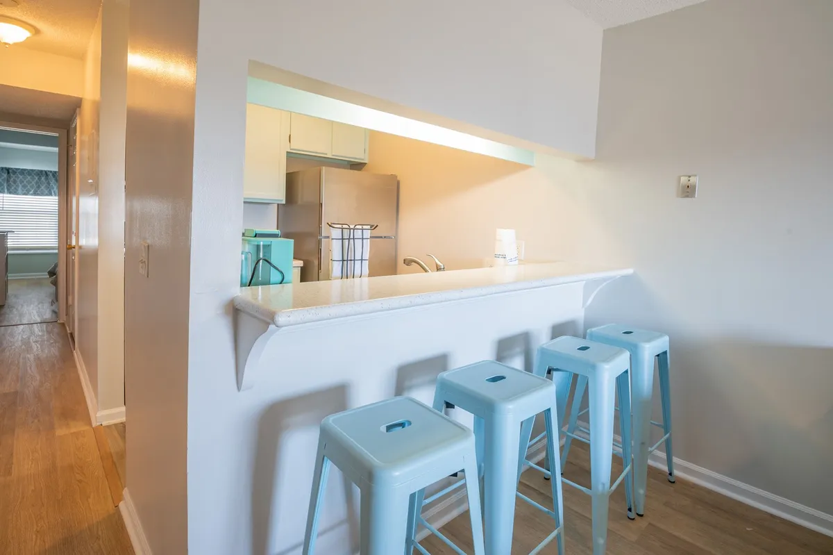A cozy kitchen scene focused on a bar counter with four stools lined up, adjacent to the kitchen area. The space encourages casual dining, friendly conversation, and shared moments over meals.