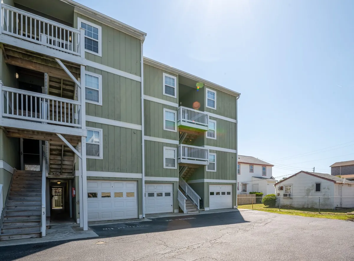The exterior shot of Sea Minnow showcases its welcoming green facade, balconies with railings, and the staircase leading upwards. The inviting outdoor setting hints at the promise of sunset views and relaxed mornings. It situates the property within its beachside neighborhood, suggesting easy access to local sights and a lively yet intimate environment.