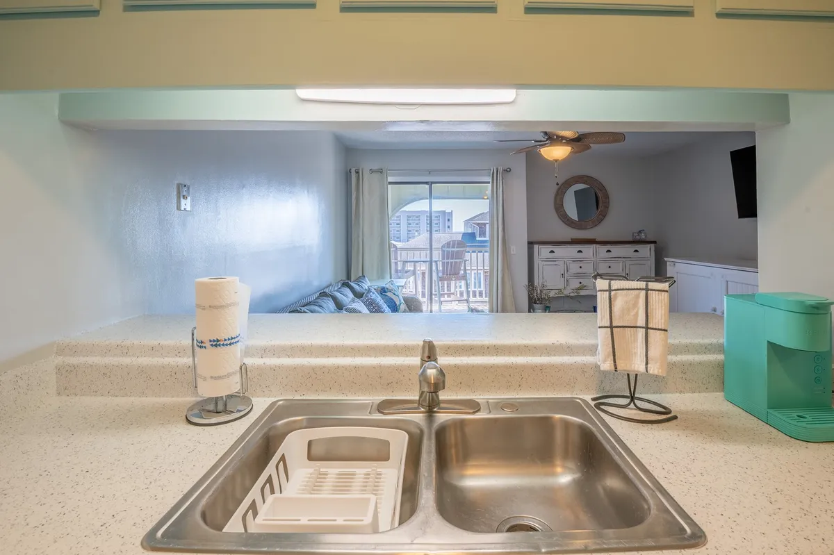 A bright, inviting kitchen with a sink, countertop, and window view. The scene highlights opportunities for cooking, entertaining, and socializing, with sunlight streaming in and a sense of openness.