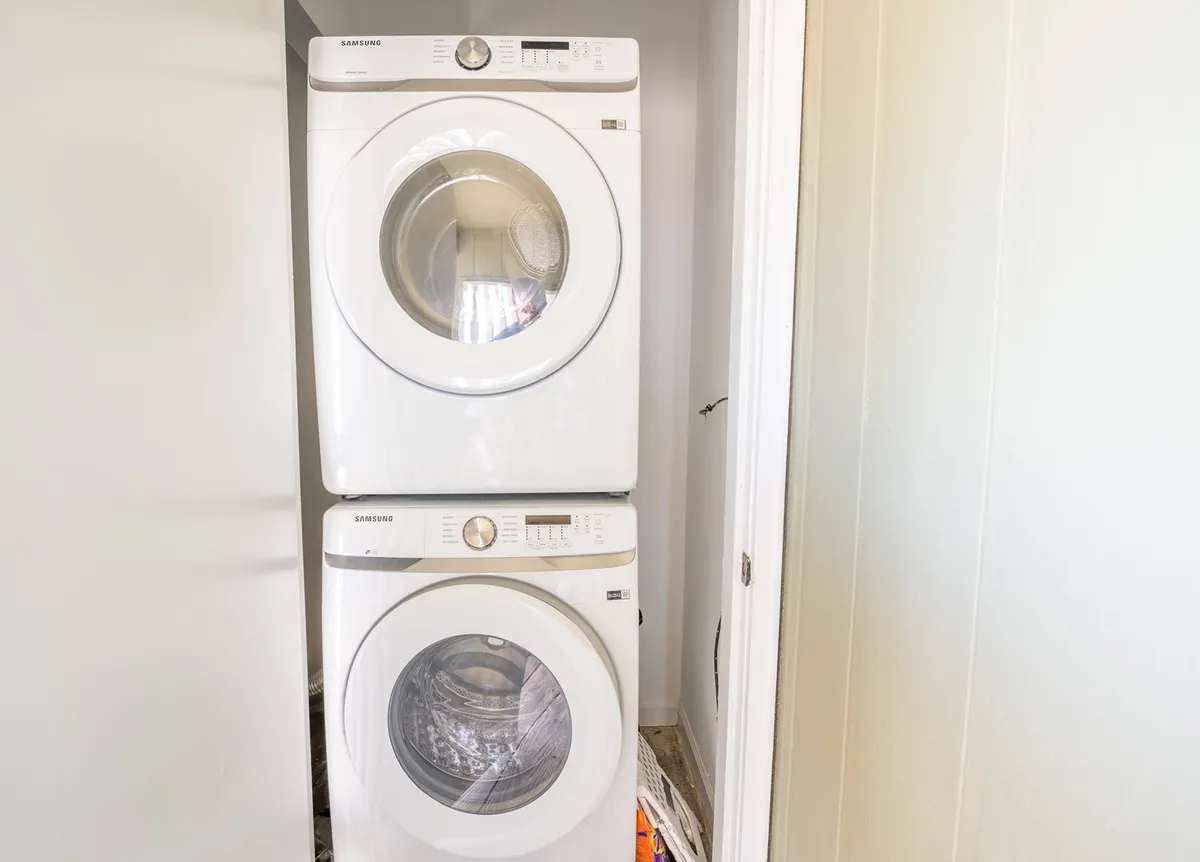 A compact but efficient in-unit stacked washer and dryer, positioned for easy access. The setup looks clean and practical, emphasizing the convenience of onsite laundry within the condo.