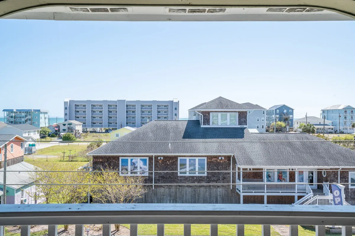 A broad, elevated view capturing the vibrant colors of nearby houses under a clear blue sky. The scene invites viewers to imagine enjoying a morning coffee on the balcony while soaking in the atmosphere of the local neighborhood.